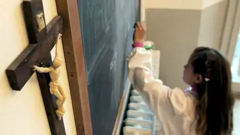 Foto de archivo de una estudiante en una clase adornada con un crucifijo en un colegio de Pisa (Italia). EFE.