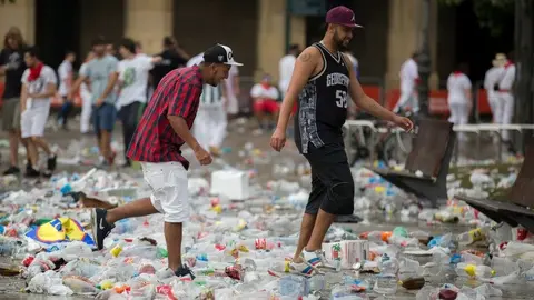 Dos j&oacute;venes atraviesan el mar de basuras de la Plaza del Castillo en Sanfermines. EFE