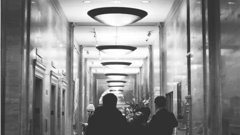 Personas esperando a un ascensor. 