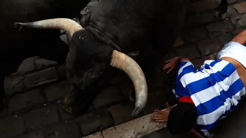 Un mozo pasa apuros ante uno de los toros de la ganadería de José Escolar, en el segundo encierro de los Sanfermines 2017. EFE Javier Lizón