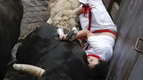 Un mozo sufre una cogida en la curva de Mercaderes durante el quinto encierro de los Sanfermines 2017, que ha sido el más rápido hasta ahora con una duración de dos minutos y doce segundos, y que ha finalizado, en principio, sin heridos por asta de toro. EFE/Villar López