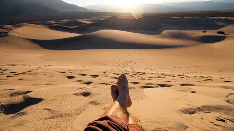 Un hombre descansa en un desierto. Jeremy Bishop. Unsplash.