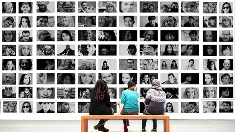 Varias personas observan una exposici&oacute;n sobre fotograf&iacute;as de otras personas