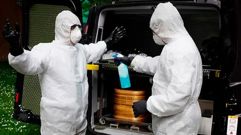 Trabajadores de un tanatorio de Pamplona desinfectan sus EPIs después de sacar del Hospital de Navarra un ataúd para proceder a su desinfección antes de trasladarlo al cementerio. La Asociación Nacional de Servicios Funerarios (PANASEF) ha enviado a Navarra material de protección frente al contagio por coronavirus para los trabajadores de los tanatorios existentes en la Comunidad foral que viven estos días "una calma tensa". Se han suministrado a las distintas empresas buzos, guantes, mascarillas, pantallas protectoras y geles hidroalcohólicos en función de las necesidades y la urgencia para intentar así asegurar la salud de los trabajadores de los tanatorios, en especial de quienes deben recoger las cuerpos de las personas fallecidas y llevarlos hasta al lugar de entierro o incineración. EFE/ Iñaki Porto