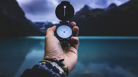 Un hombre sostiene una brújula en una montaña.