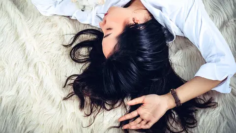 Una mujer descansa dormida en una cama. ARCHIVO