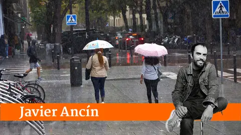 Varias personas caminan bajo la lluvia la plaza de la Cruz en el II Ensanche de Pamplona. I&Ntilde;IGO ALZUGARAY