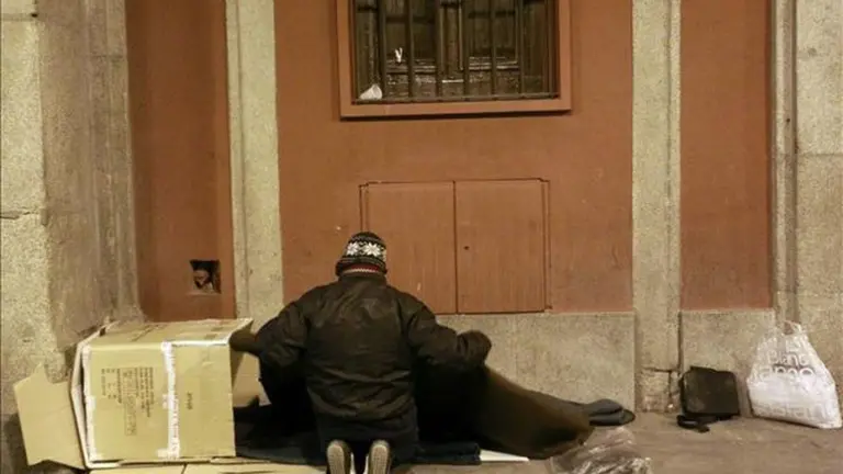 Un indigente se dispone a pasar la noche en un porche. EFE.