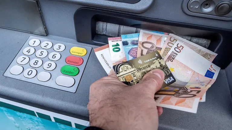 Un hombre extrae dinero del cajero de un banco con una tarjeta de crédito. ARCHIVO