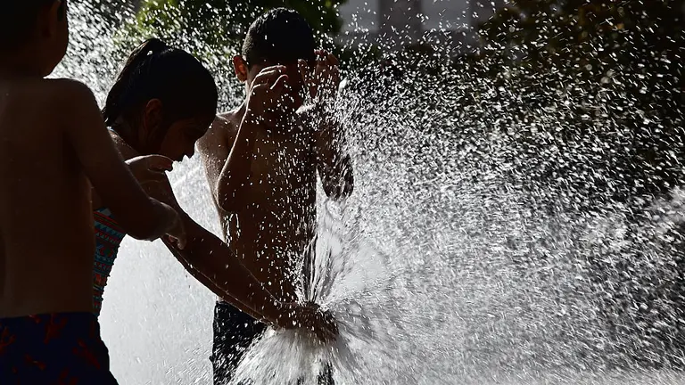 Unos ni&ntilde;os juegan en la 'fuente de chorros' de la Plaza de Yamaguchi durante la primera ola de calor del verano en Pamplona. I&Ntilde;IGO ALZUGARAY
