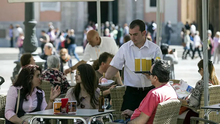 Un camarero, empleado en el sector servicios, sirve unas cervezas y un helado a varios clientes en la terraza de un bar EFE Archivo