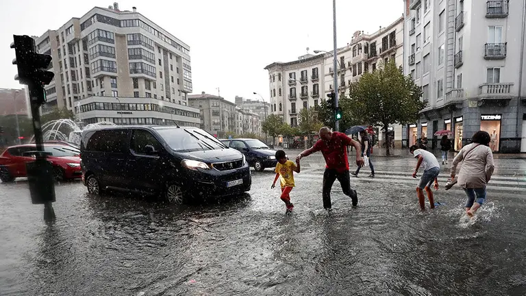 GRAFCAV8054. PAMPLONA (NAVARRA), 18/09/2019.- Varias personas cruzan la Avenida Baja Navarra que se encuentra inundada de agua tras la fuerte tormenta de esta tarde que ha ocasionado numerosas balsas en las carreteras y donde los bomberos han realizado numerosas salidas para achicar agua en Pamplona. EFE/ Jes&uacute;s Diges