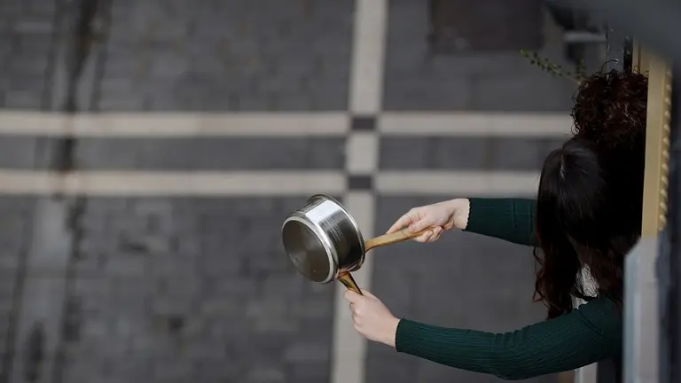 GRAFCAV3630. PAMPLONA, 18/03/2020.- Una joven hace sonar un cazo desde su balc&oacute;n durante la "cacerolada" celebrada este mediod&iacute;a en Pamplona que, en medio de la crisis mundial por el coronavirus, ha querido pedir de esta manera al rey em&eacute;rito Juan Carlos I que done a la sanidad p&uacute;blica los 100 millones de euros que supuestamente tendr&iacute;a en cuentas de Suiza y que provendr&iacute;an del rey saud&iacute;. EFE/Villar L&oacute;pez.