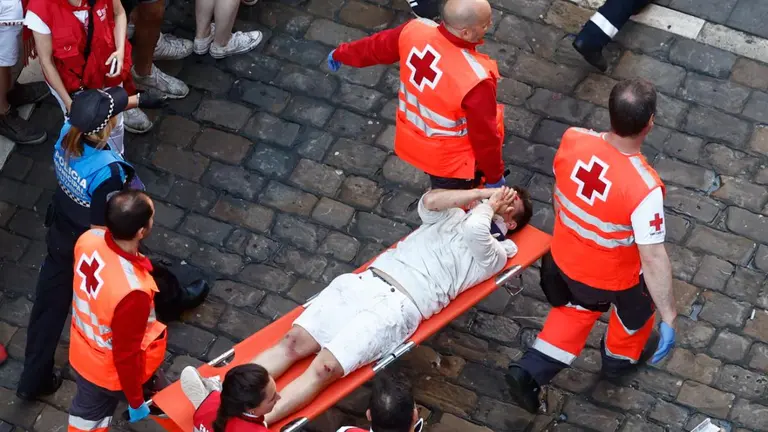Sanitarios de Cruz Roja trasladan a uno de los mozos que ha resultado herido tras corren ante los toros de la ganader&iacute;a de Jos&eacute; Escolar durante el tercer del encierro de San Ferm&iacute;n, este s&aacute;bado. EFE/ Rodrigo Jimenez