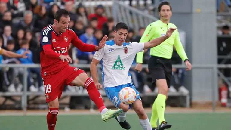 FUENTES DE EBRO (Zaragoza), 12/11/2022.- El defensa del Fuentes, Rubio (d), disputa el bal&oacute;n ante el delantero de Osasuna, Kike Garc&iacute;a, durante la primera eliminatoria de la Copa del Rey disputado hoy S&aacute;bado en el estadio San Miguel en la localidad aragonesa de Fuentes de Ebro.  EFE / Javier Cebollada.

