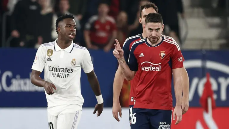 El delantero brasileño del Real Madrid, Vinicius Jr. (i) y el delantero de Osasuna, Moi Gómez, conversan al termino del primer tiempo del encuentro correspondiente a la jornada 22 de primera división que disputan hoy sábado en el estadio El Sadar de Pamplona. EFE / Jesus Diges.
