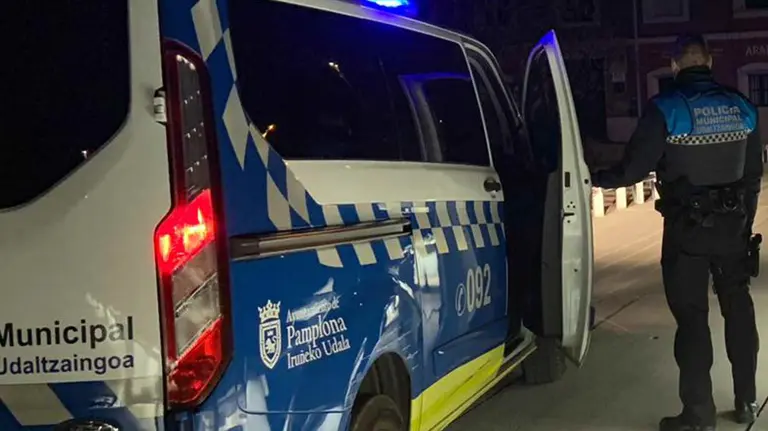 Un agente de la Policía Municipal de Pamplona ante un coche patrulla. POLICÍA MUNICIPAL DE PAMPLONA
