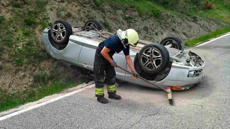 Un bombero del parque de Cordovilla limpia la calzada ante el veh&iacute;culo siniestrado. BOMBEROS DE NAVARRA
