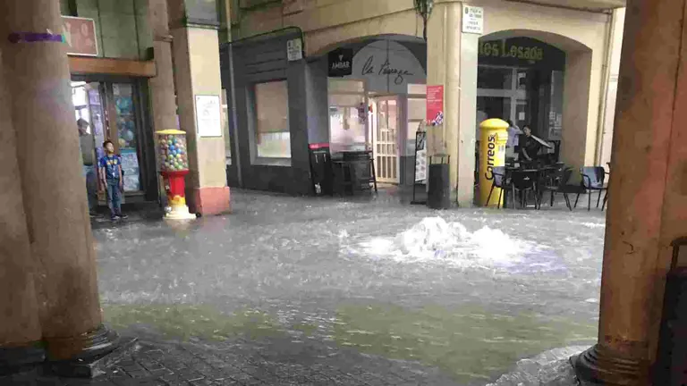 Agua saliendo a borbotones por una alcantarilla en la Plaza de los Fueros de Estella.