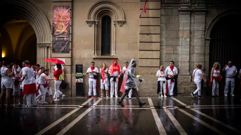 Varias personas se resguardan de la lluvia en el primer d&iacute;a de los San Fermines 2023 en Pamplona. JASMINA AHMETSPAHIC