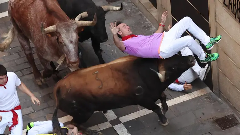 Un mozo volteado por un toro, en el tramo la curva de Mercaderes al inicio de Estafeta, durante el cuarto encierro de los sanfermines 2023 protagonizado este lunes por la ganader&iacute;a de Fuente Ymbro, un recorrido de 2 minutos y 21 segundos de duraci&oacute;n. EFE/J.P. Urdiroz