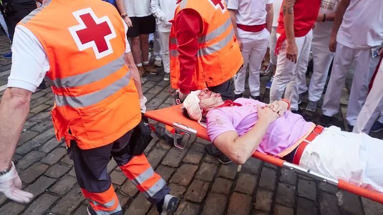 Dos sanitarios llevan en camilla a un herido en el cuarto encierro de las fiestas de San Ferm&iacute;n 2023, a 10 de julio de 2023, en Pamplona. EDUARDO SANZ / EUROPA PRESS
