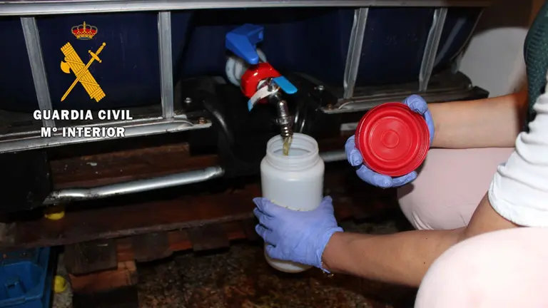 Un agente del SEPRONA toma muestras del aceite ilegal que se vend&iacute;a en Cintru&eacute;nigo. GUARDIA CIVIL