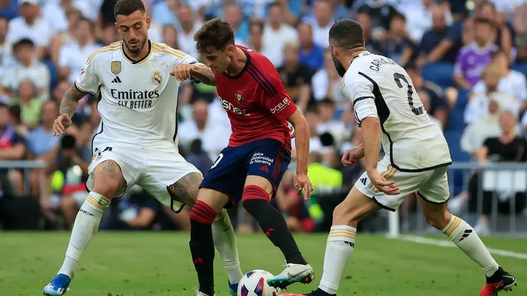 MADRID, 07/10/2023.- El centrocampista del Osasuna Aimar Oroz (C) con el bal&oacute;n ante los jugadores del Real Madrid Joselu (i) y Dani Carvajal durante el partido de Liga EA Sports que el Real Madrid y el Osasuna disputan este s&aacute;bado en el estadio Santiago Bernab&eacute;u de Madrid. EFE/Zipi
