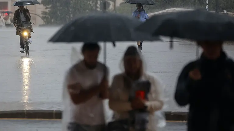 Varias personas se resguardan bajo un paraguas de la lluvia, el viento y el mal tiempo. ROBER SOLSONA / EUROPA PRESS