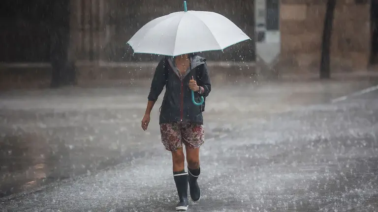 Varias personas se resguardan bajo un paraguas de la lluvia, el viento y el mal tiempo. ROBER SOLSONA / EUROPA PRESS