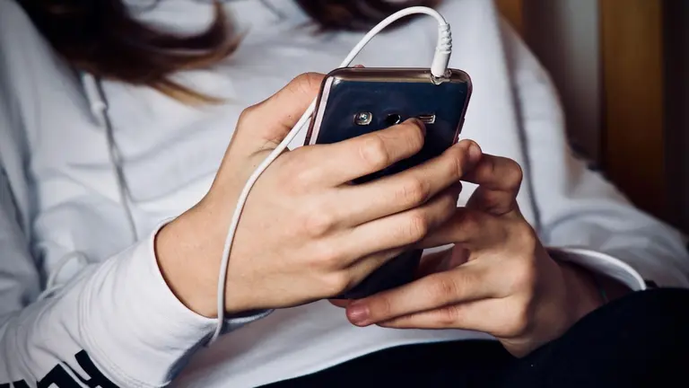 Imagen de archivo de una ni&ntilde;a con un tel&eacute;fono m&oacute;vil. ARCHIVO