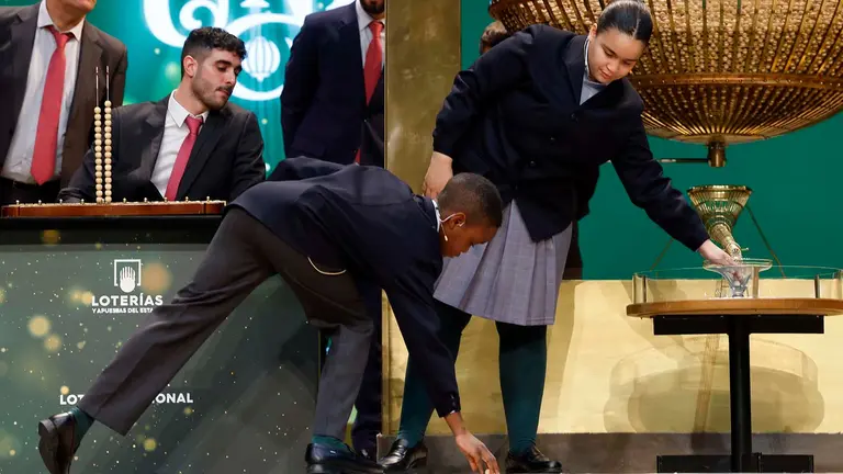 Uno de los ni&ntilde;os de San Ildefonso recoge la bola que se le ha ca&iacute;do durante el sorteo extraordinario de Navidad de la Loter&iacute;a Nacional este viernes en el Teatro Real de Madrid. EFE/ J.J. Guill&eacute;n