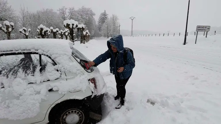 Una persona limpia de nieve su veh&iacute;culo en la localidad de Roncesvalles en una jornada donde la normalidad es la nota dominante en las carreteras navarras a primeras horas de este mi&eacute;rcoles en el que la Comunidad Foral est&aacute; en alerta por nevadas. As&iacute;, tan solo son necesarias las cadenas para circular por la NA-137 Burgui-Isaba-Francia, puerto de Belagua, desde el kil&oacute;metro 51, desde el refugio. EFE/ Jes&uacute;s Diges