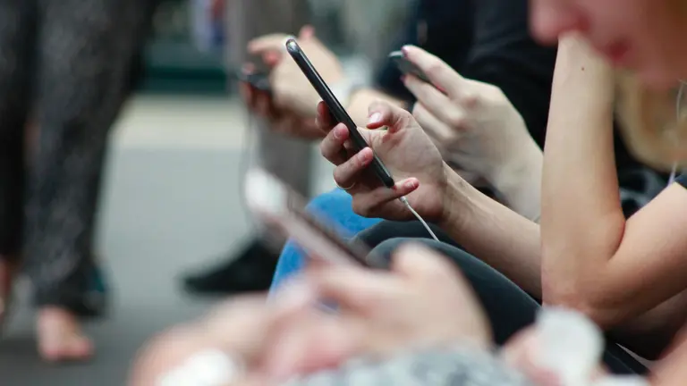Varias personas consultan sus tel&eacute;fonos m&oacute;viles en una imagen de archivo.