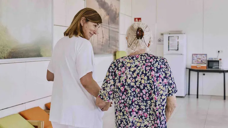 Una anciana acompa&ntilde;ada `por su cuidadora en una residencia de la tercera edad. FUNDACI&Oacute;N LA CAIXA