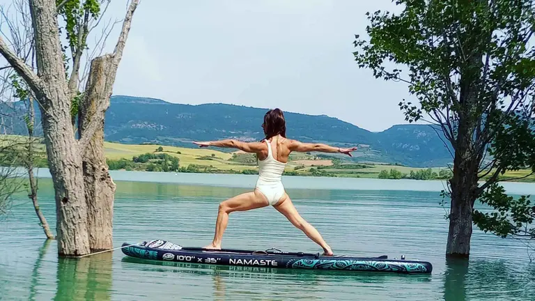 Sesi&oacute;n de yoga sobre una tabla de surf en la orilla del pantano de Alloz. TIERRAS DE IRANZU