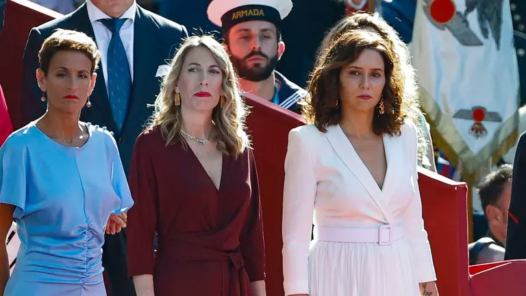 La presidenta de Navarra María Chivite (i-d), la presidenta de la Junta de Extremadura, María Guardiola, y la presidenta de la comunidad de Madrid, Isabel Díaz Ayuso, este jueves durante el desfile del Día de la Fiesta Nacional en Madrid, presidido por los reyes, en el que participan 4.177 militares, 86 aviones y helicópteros y 142 vehículos terrestres.EFE/ Chema Moya