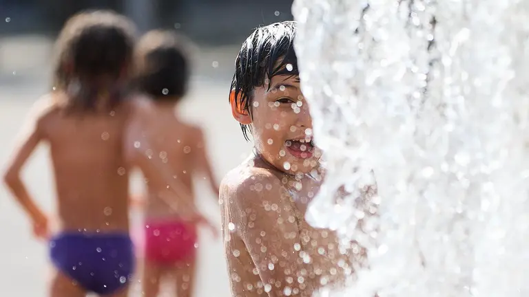 Unos niños juegan en la Fuente de los Chorros en el parque de Yamaguchi de Pamplona en el primer día de una nueva ola de calor de este verano. IÑIGO ALZUGARAY