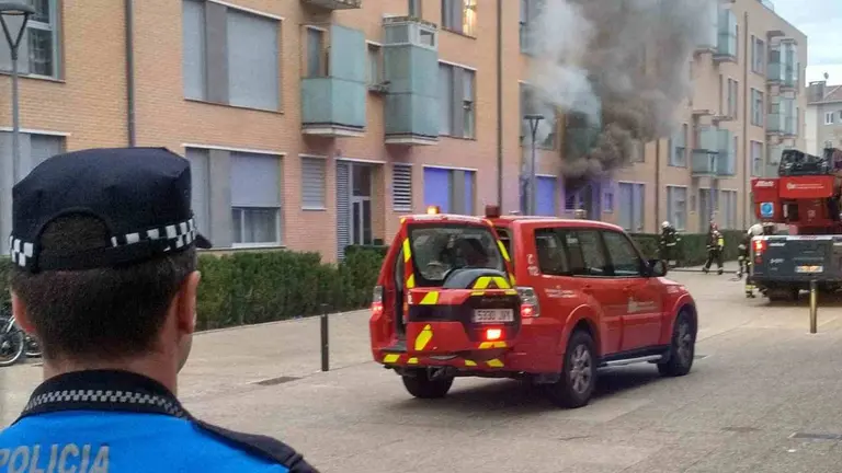 Un agente de la Polic&iacute;a Municipal de Pamplona y efectivos de bomberos ante el domicilio incendiado. POLIC&Iacute;A MUNICIPAL DE PAMPLONA