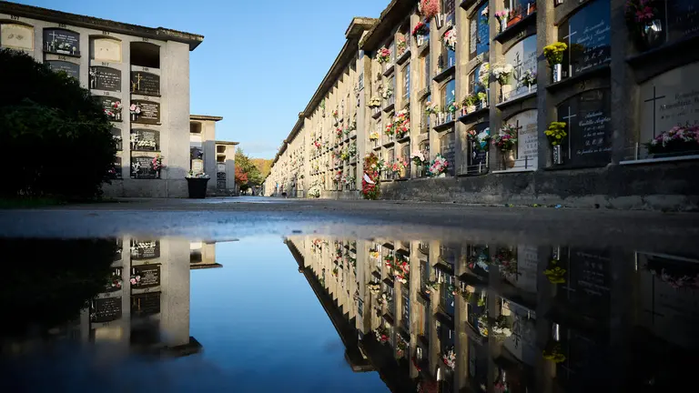 Varias personas llevan flores a sus sere queridos durante la celebración de Todos los Santos en el cementerio de Pamplona. PABLO LASAOSA