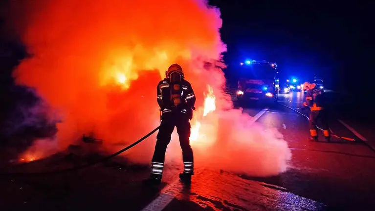 Un bombero sofoca el incendio del coche en plena calzada. BOMBEROS DE NAVARRA