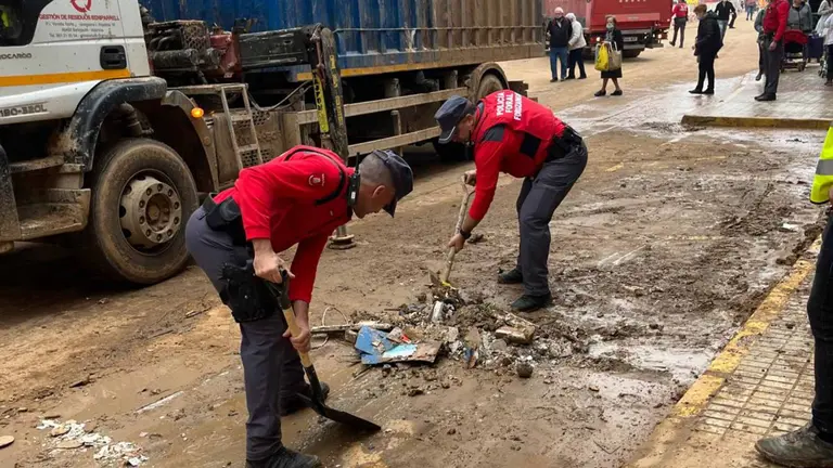 Dos agentes de la Polic&iacute;a Foral retirando lodo y barro de las calles de Paiporta, en Valencia. POLIC&Iacute;A FORAL