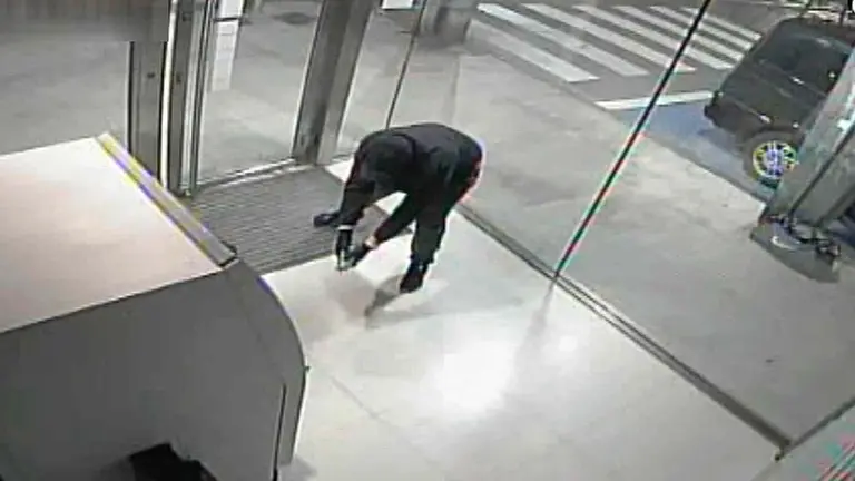 Imagen de la cámara de seguridad de uno de los cajeros que capta el momento en el que el atracador prende el artefacto explosivo. GUARDIA CIVIL