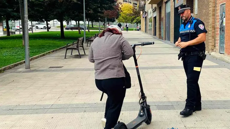 Un agente de la Polic&iacute;a Municipal de Pamplona junto a la conductora de un patinete el&eacute;ctrico que circulaba sobre la acera. POLIC&Iacute;A MUNICIPAL DE PAMPLONA
