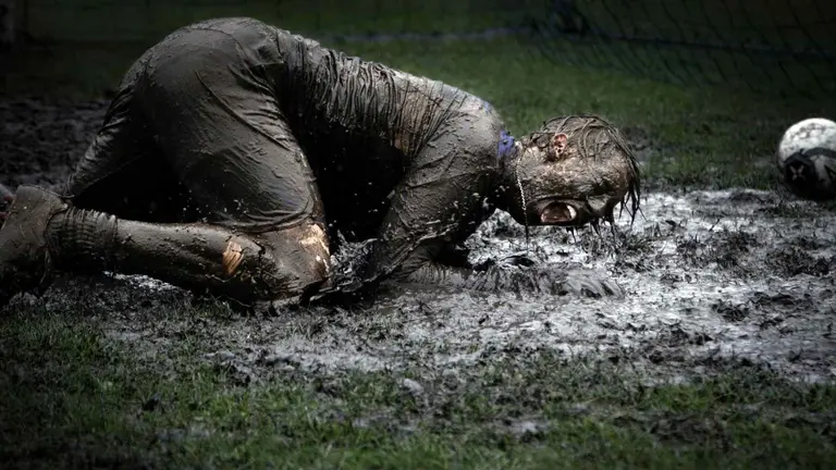 Un joven jugando al f&uacute;tbol sobre un campo de barro. VIDAR NORDLI-UNSPLASH