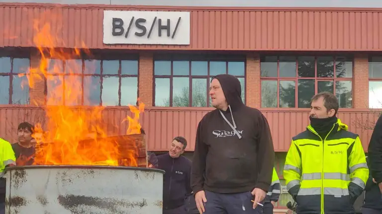 Una valla y un bid&oacute;n con fuego impide la entrada de camiones de proveedores a las instalaciones de la empresa BSH en Esqu&iacute;roz. LAB