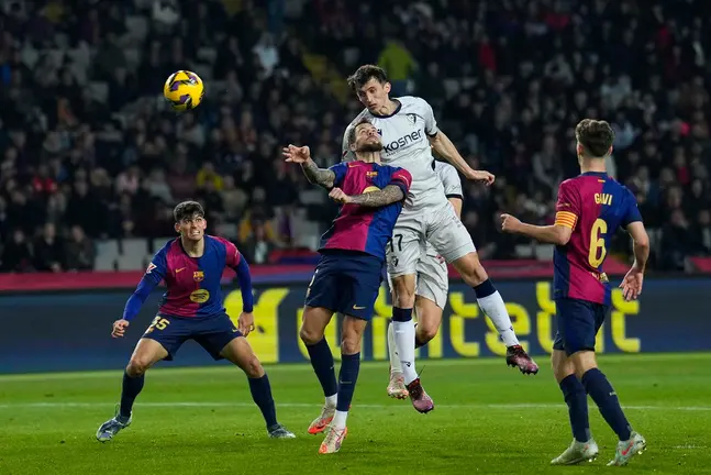 BARCELONA, 27/03/2025.- El delantero de Osasuna Ante Budimir (2d) remata de cabeza junto a Íñigo Martínez, del FC Barcelona, durante el partido de la jornada 27 de LaLiga que FC Barcelona y Atlético Osasuna disputan hoy jueves en el Estadio Olímpico Lluís Companys. EFE/Alejandro García