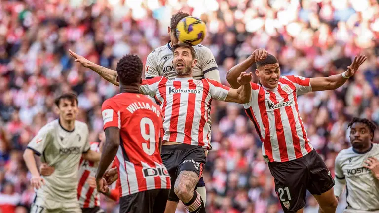 El defensa del Athletic Club de Bilbao Yeray Álvarez (c) intenta despejar el balón de cabeza, durante el partido de la jornada 29 de LaLiga que Athletic Club y Atlético Osasuna disputan este domingo en el estadio de San Mamés. EFE/Javier Zorrilla