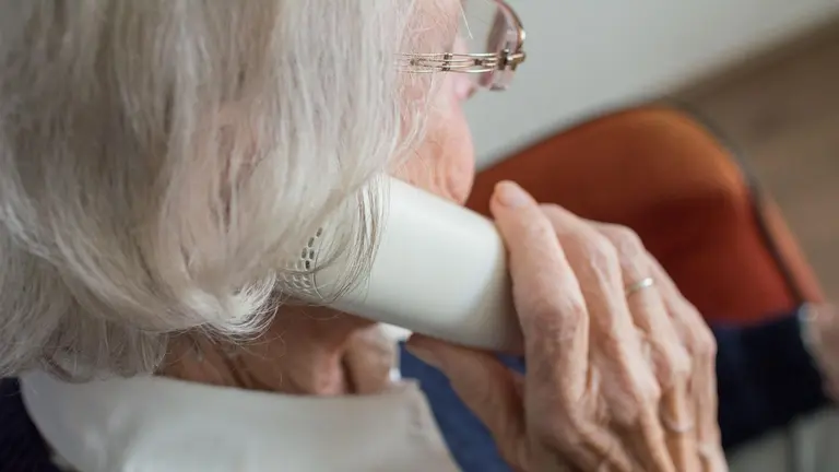 Imagen de una mujer mayor con canas hablando por teléfono. ARCHIVO