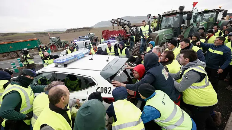 Agricultores mueven coches de la Guardia Civil para acceder a Pamplona este jueves. Por tercer día consecutivo agricultores y ganaderos han salido desde primera hora de la mañana con sus tractores a las carreteras navarras. Agricultores en toda España protestan este jueves por tercer día consecutivo para demandar una relajación de las exigencias medioambientales impuestas desde la Unión Europea, acuerdos comerciales con terceros países más justos, reciprocidad en los alimentos de terceros países y ayudas para crisis como la generada por la sequía.
